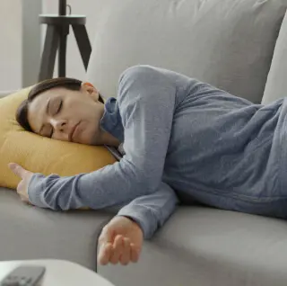 Frau beim Powernap auf dem Sofa