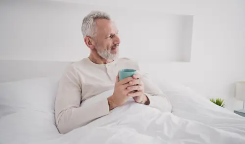 Senior mit Kaffee im Bett