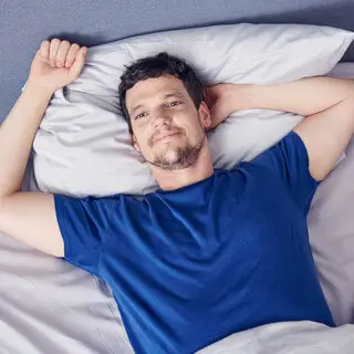 Junger Mann liegt lächelnd im Bett