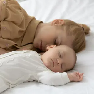 Frau liegt mit Baby im Bett