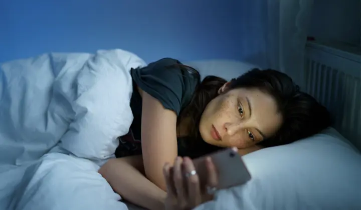 Frau mit Handy im Bett