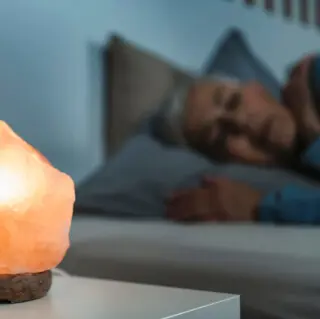 Frau schläft neben leuchtender Salzkristalllampe