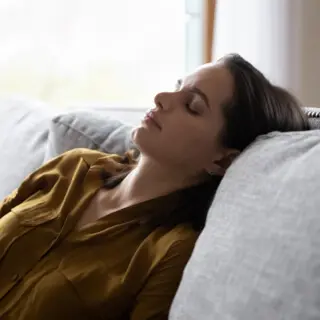 Frau mit geschlossenen Augen auf dem Sofa