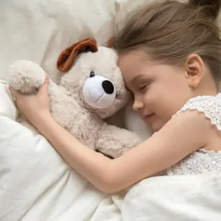 Mädchen mit Teddy im Bett