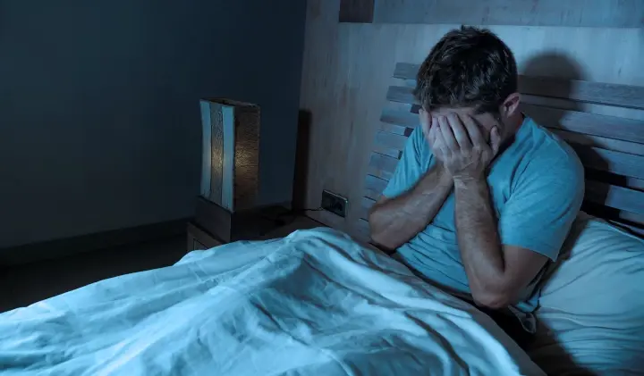 Mann sitzt verzweifelt im Bett