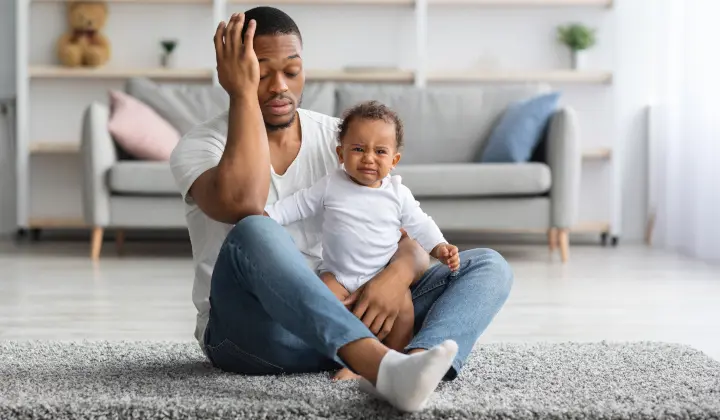 Erschöpfter Vater hält weinendes Baby