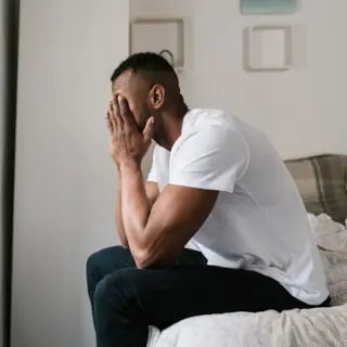 Mann sitzt müde auf der Bettkante