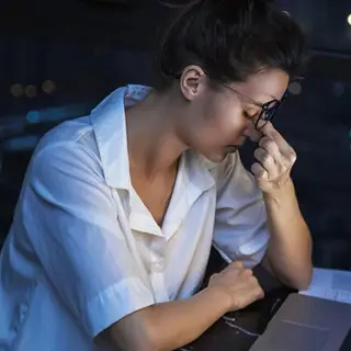 Frau sitzt müde am Laptop
