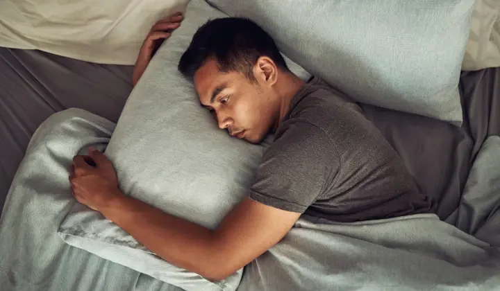 Mann liegt wach im Bett